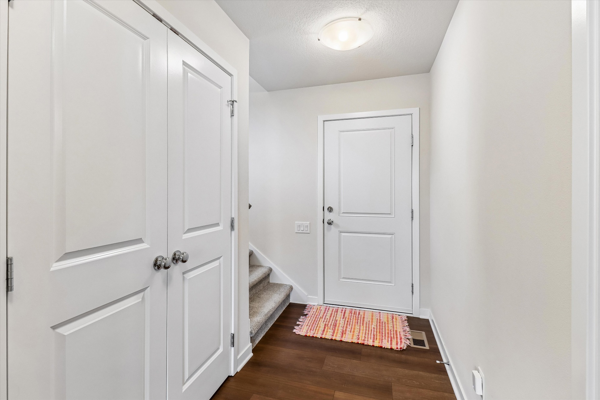 Foyer with hardwood floors, coat closet, and stairs up