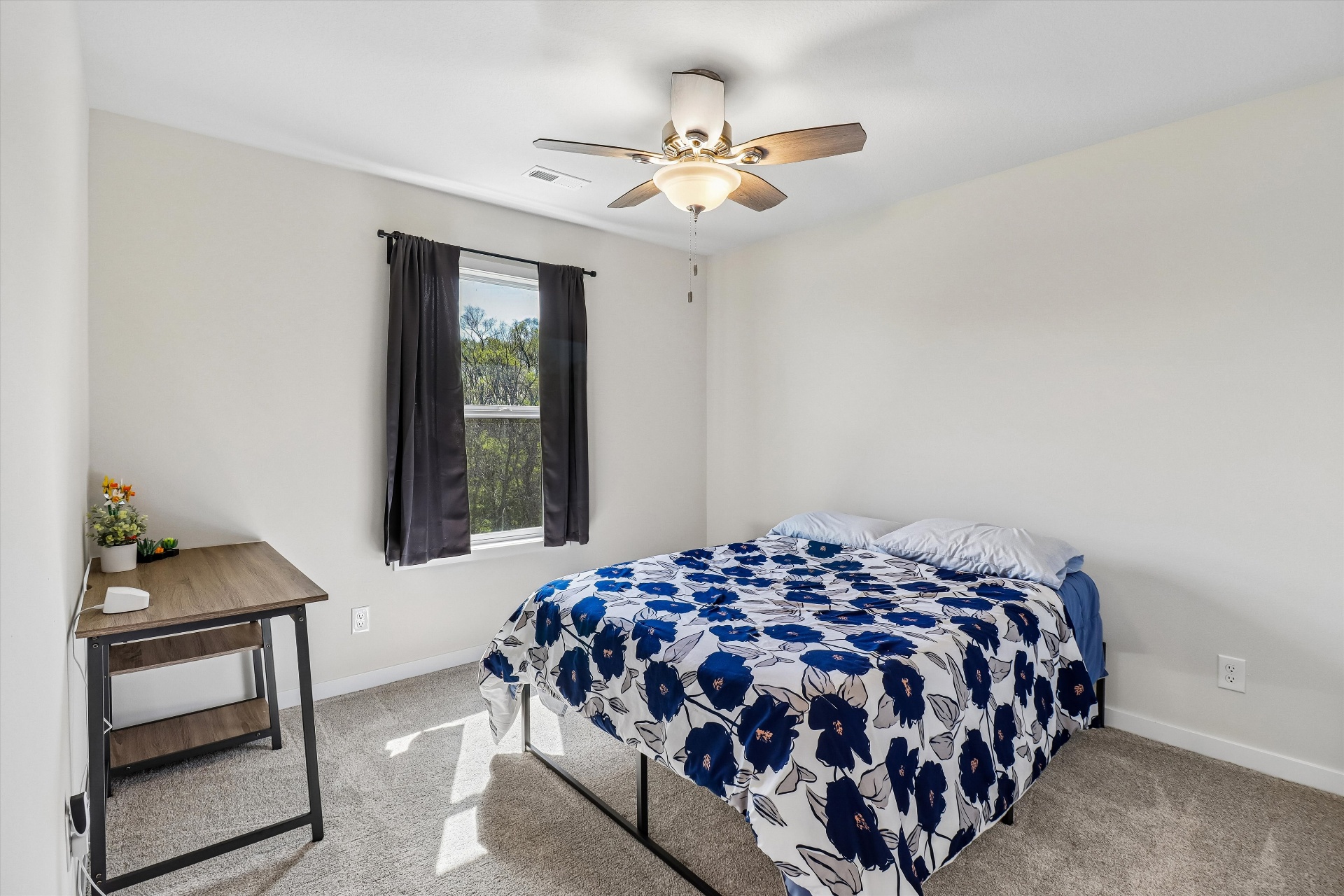 Secondary bedroom with ceiling fan and treetop views